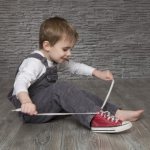 Четырехлетний мальчик завязывает шнурки