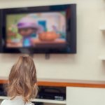 Девочка смотрит мультик по телевизору